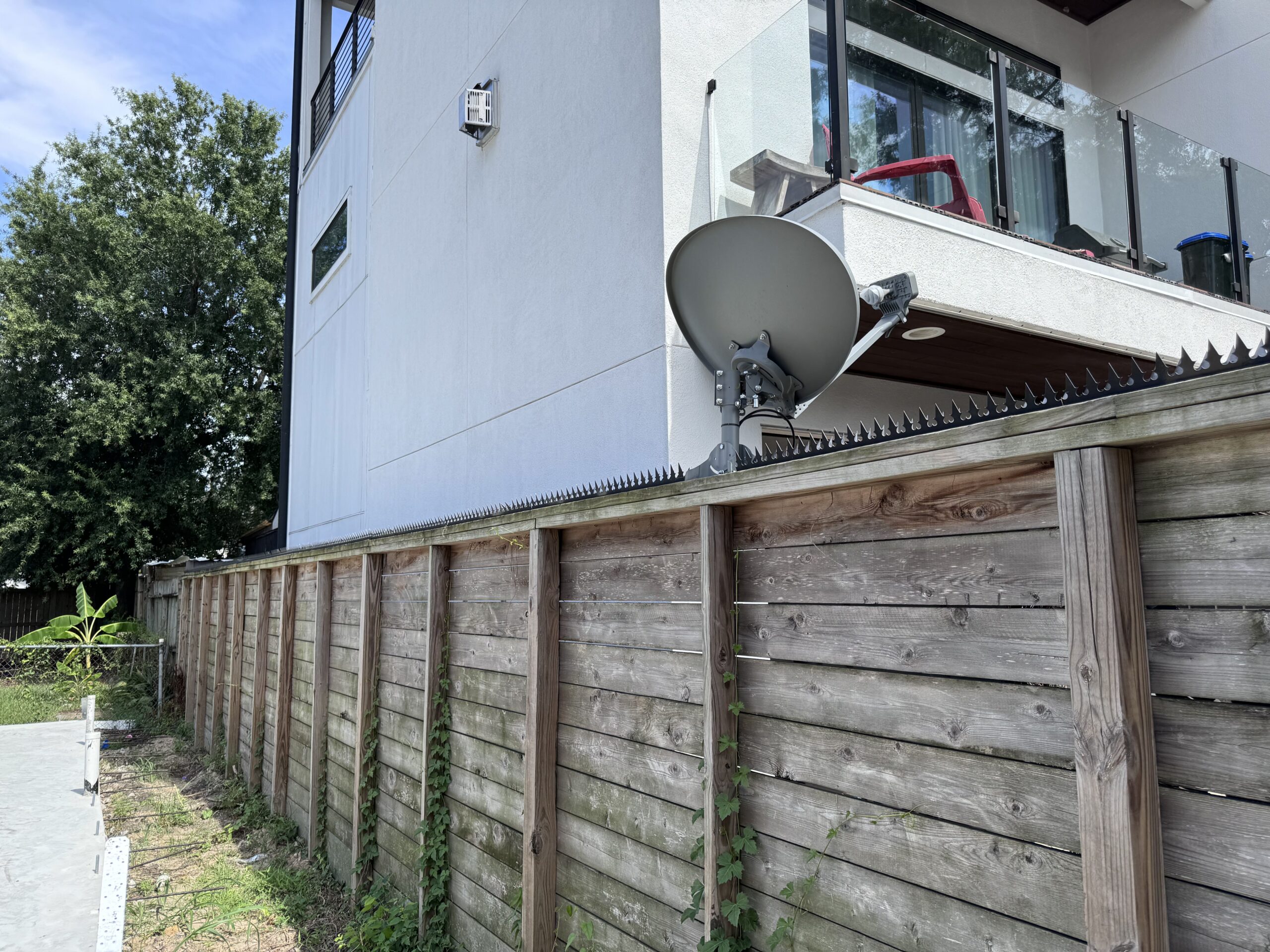 Larga cerca negra de privacidad con pinchos anti-intrusion frente a una vivienda moderna.