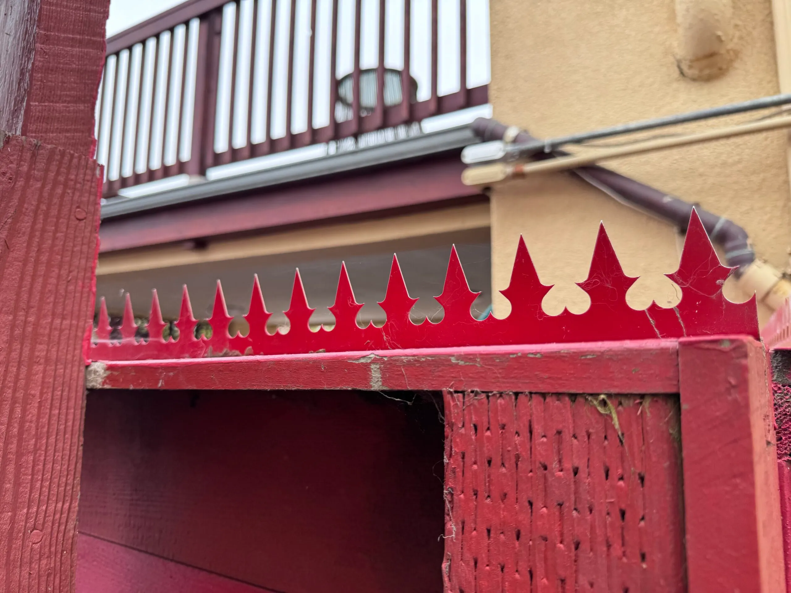 Detail of the fence corner. The image shows the relationship between the red spikes and the adjacent exterior wall.