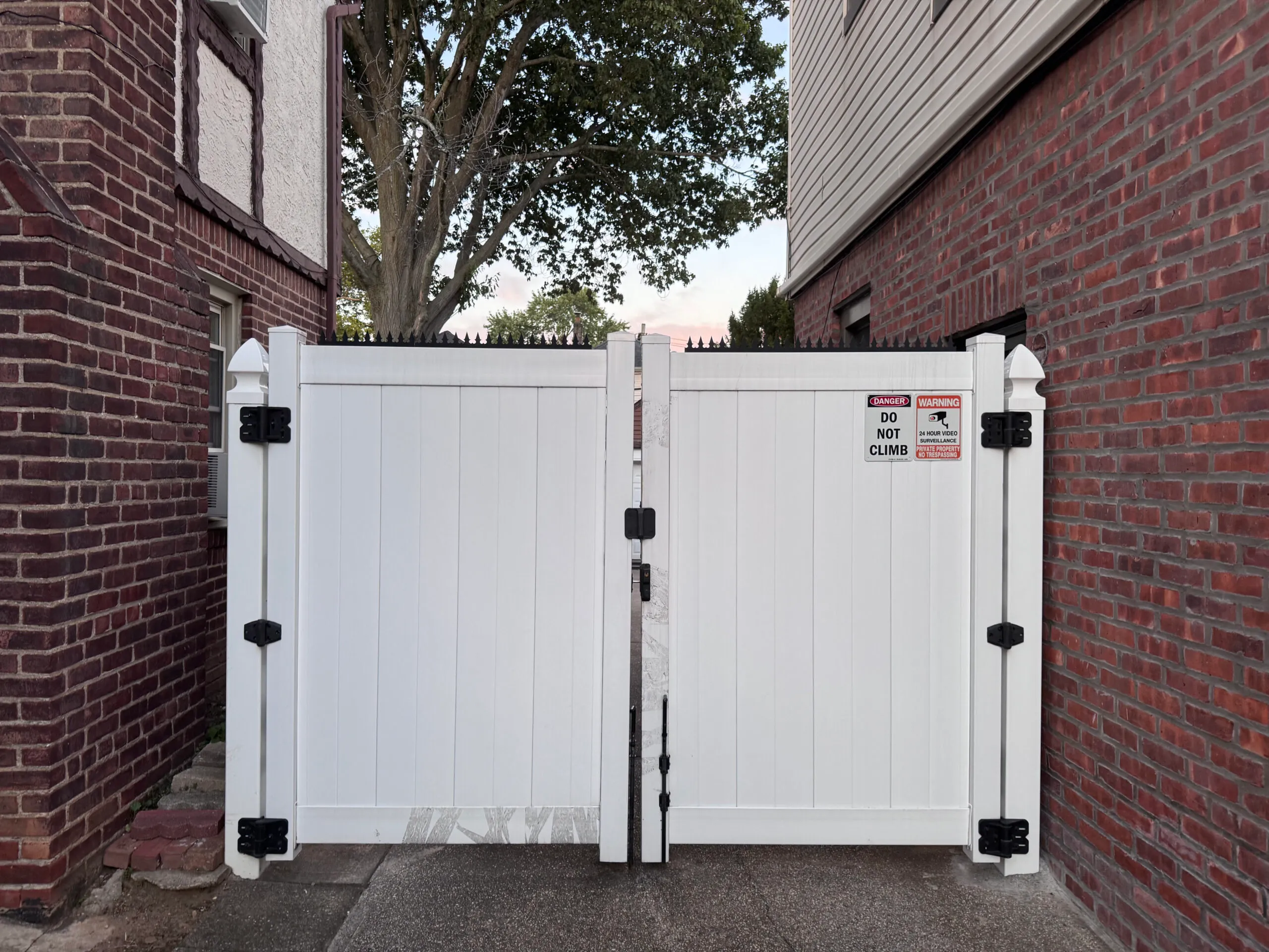 White wooden double gate. Ninja Deterrent™ anti-climb spikes installed on the top.