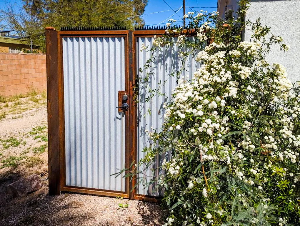 Corrugated metal gate viewed from the front. Black spikes cover the entire width of the gate.