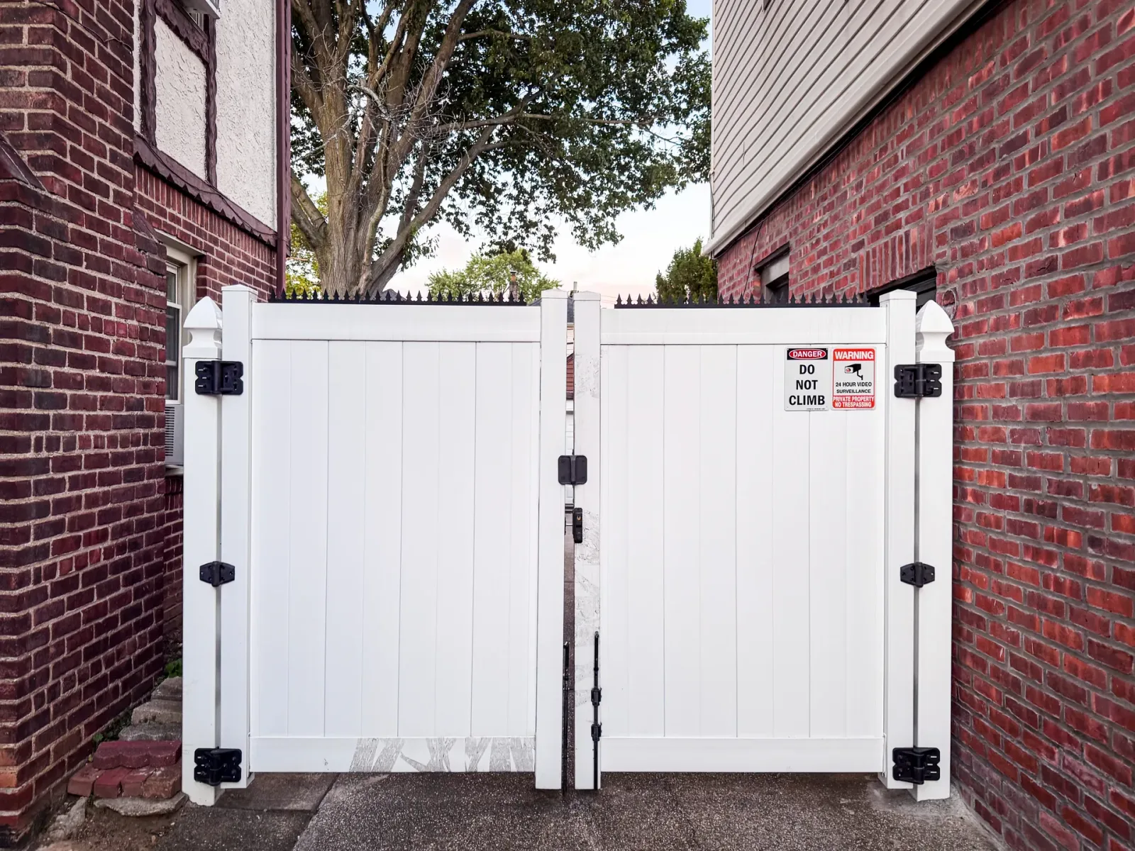 White wooden double gate. Ninja Deterrent® anti-climb spikes installed on the top.
