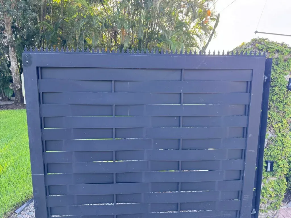 Nahaufnahme von Anti-Kletter-Spikes auf einem schwarzen Metalltor mit horizontalen Lamellen
