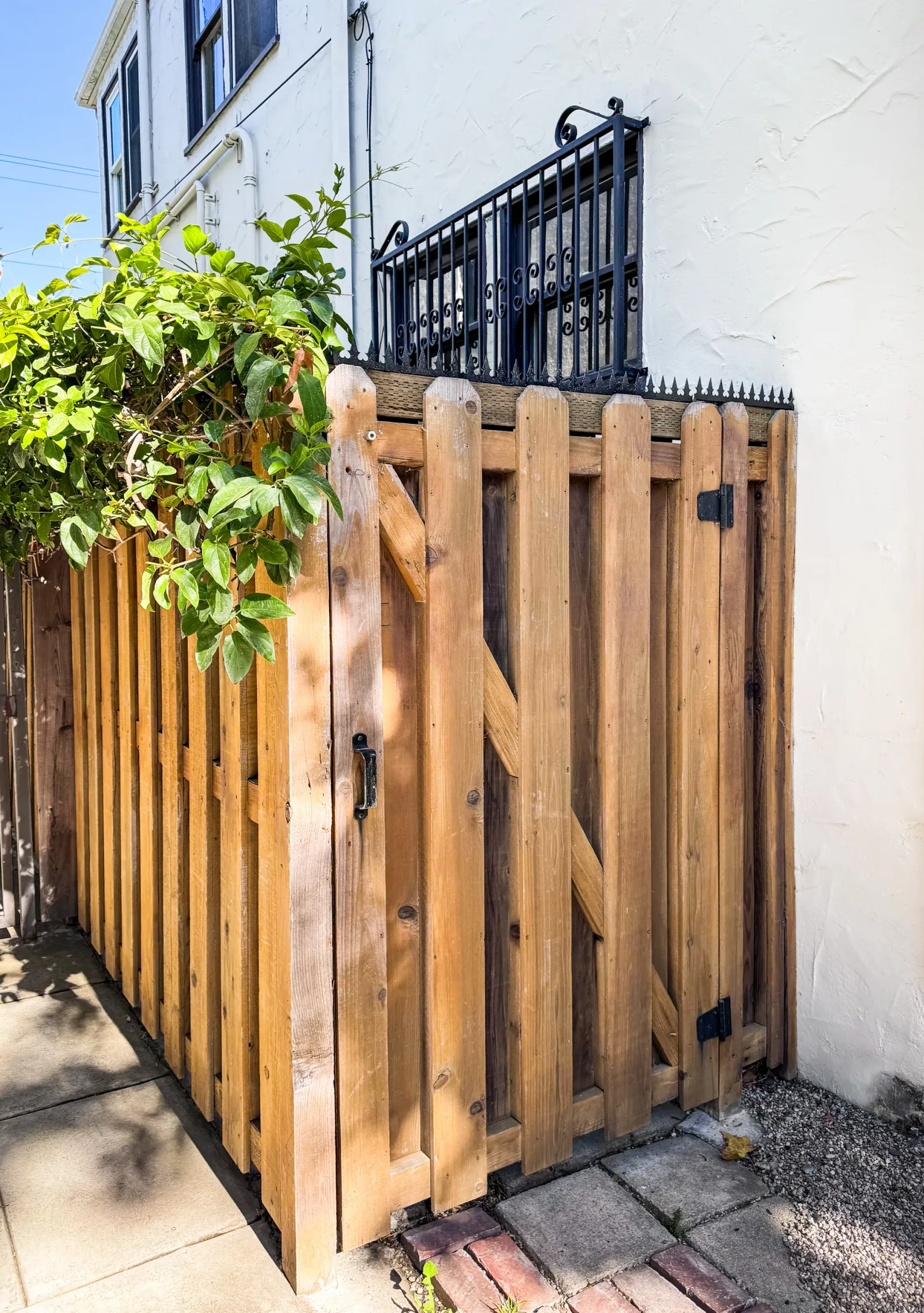 Full view of the narrow side yard entrance. The wooden gate, fence and anti-climb spikes are seen as a unified element.