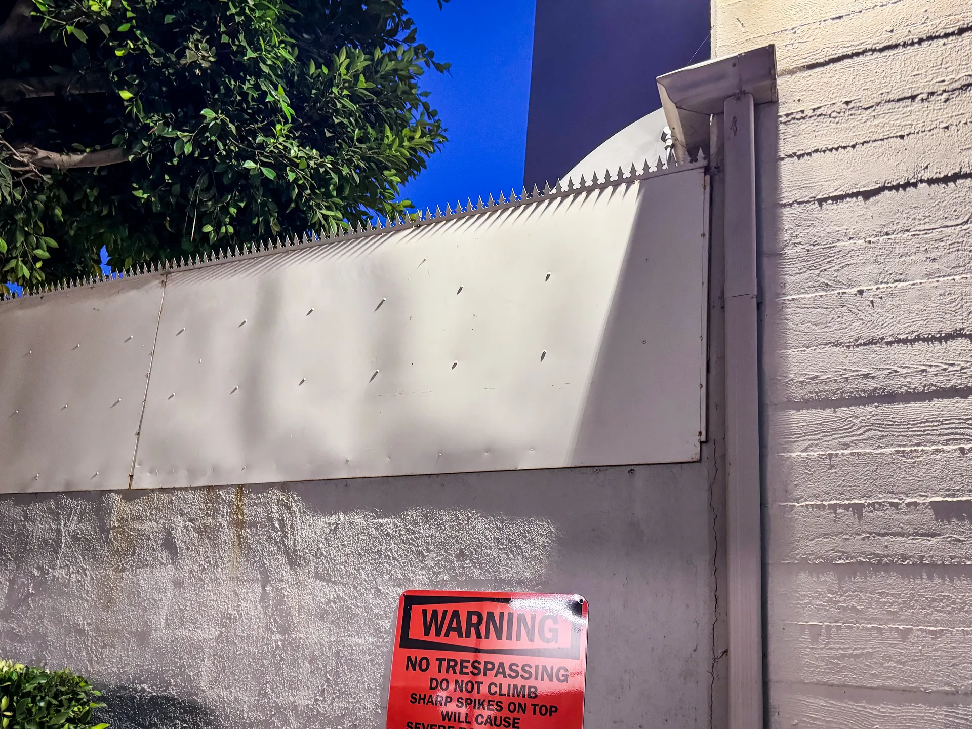 Warning sign mounted on the wall beneath the spiked top rail