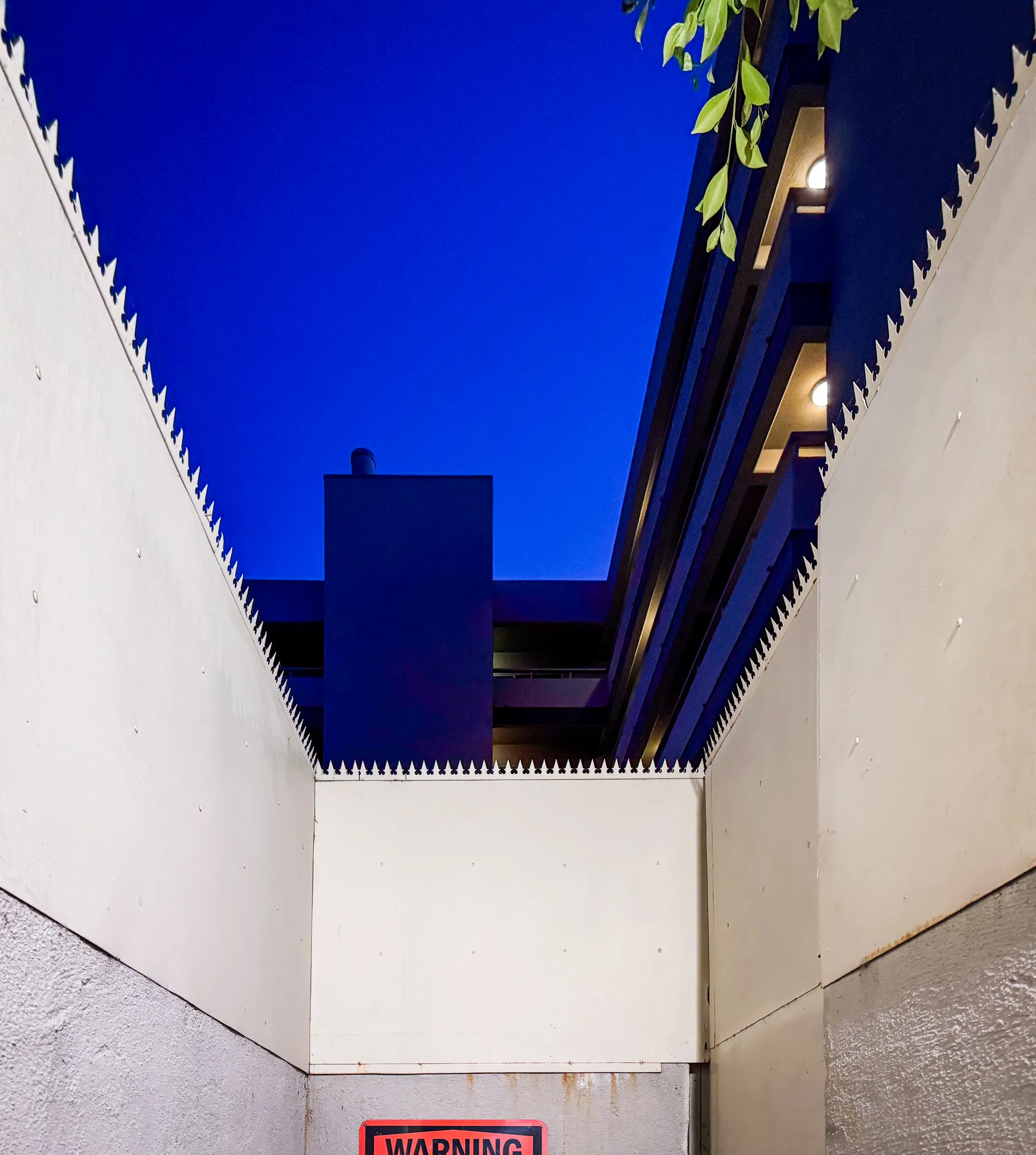 Sloped wall section with spikes and a posted warning sign