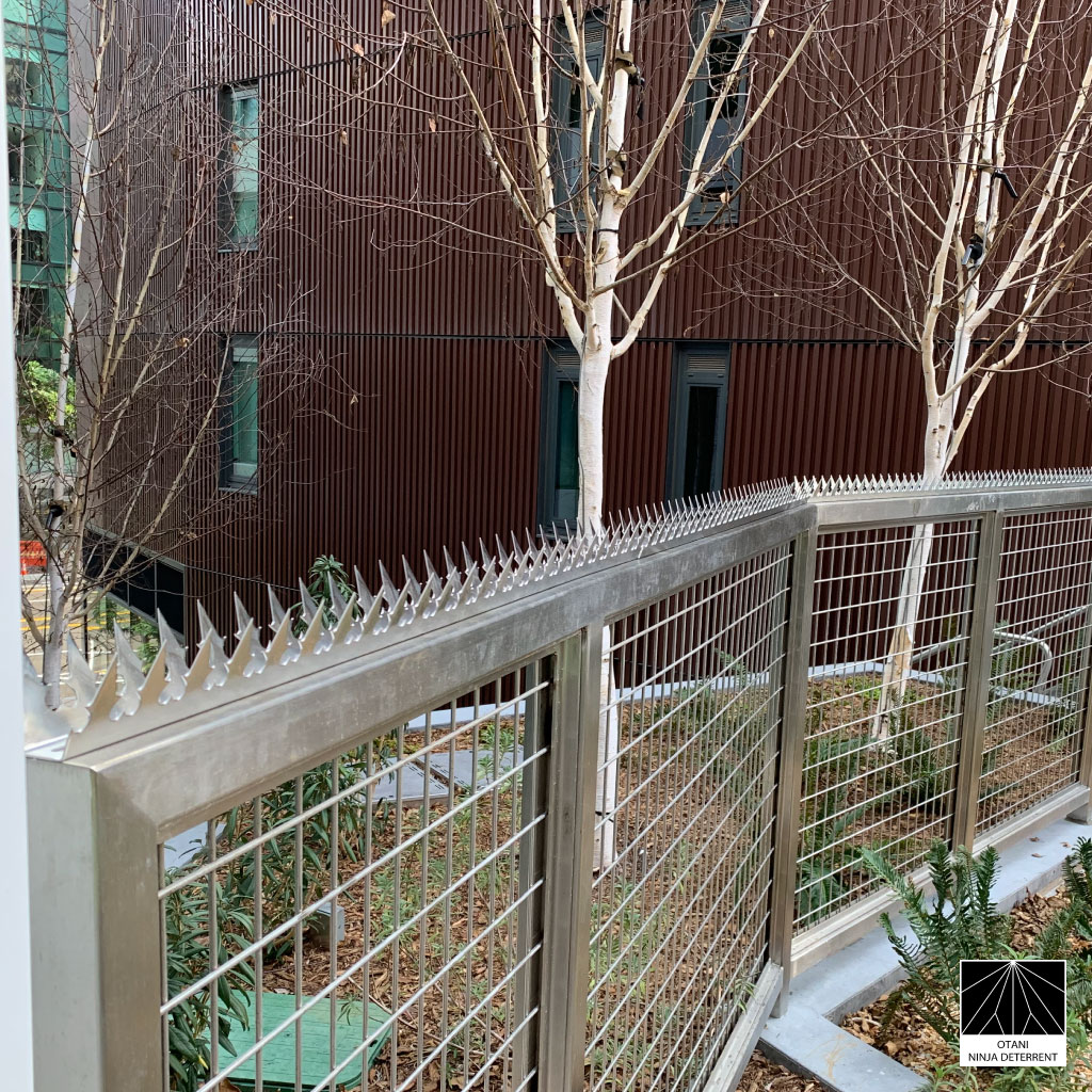 GIZAGIZA stainless steel heart-shaped security spikes installed on a modern mesh gate – Japanese-made deterrent blending safety and architectural design
