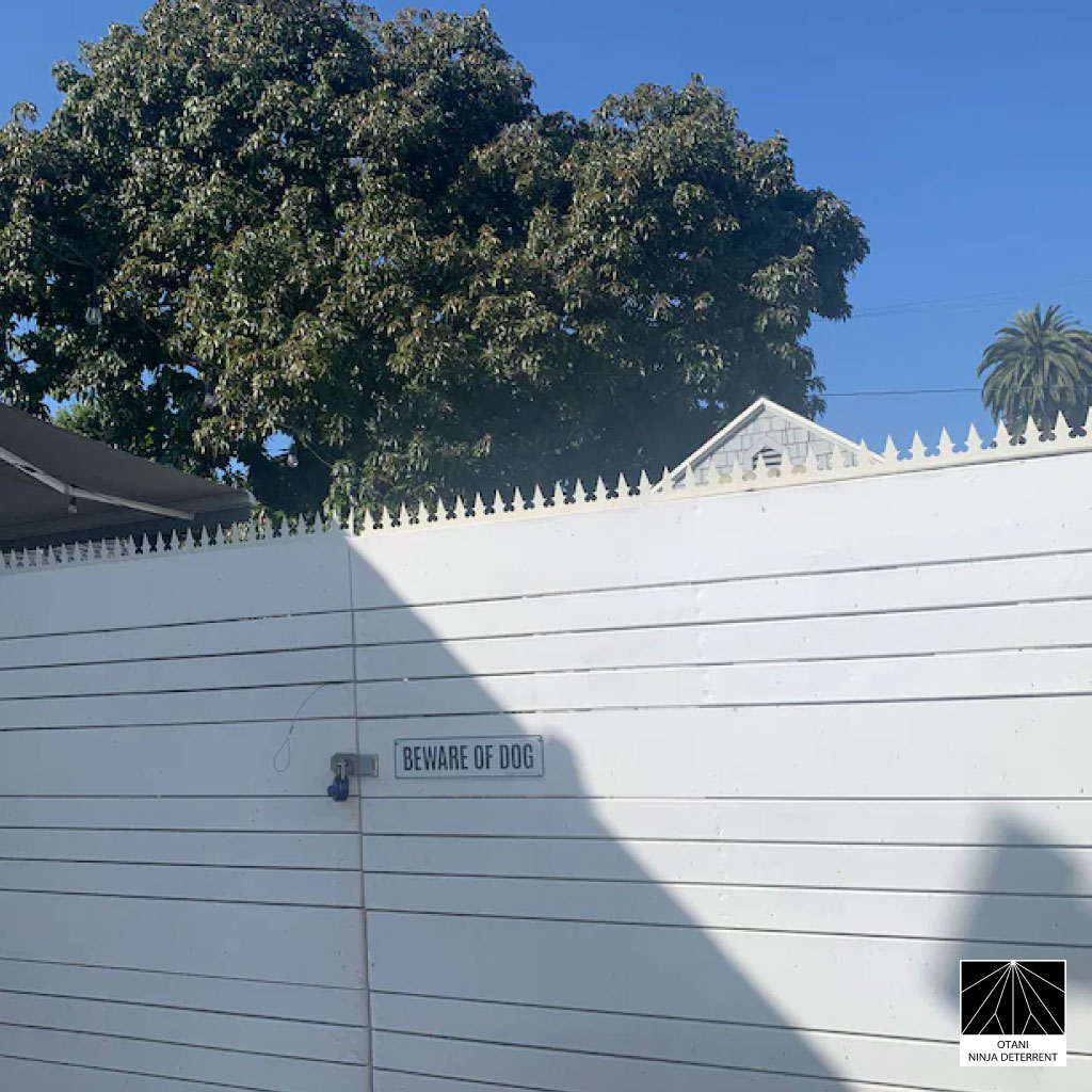 GIZAGIZA white heart-shaped security spikes installed on a white gate with “Beware of Dog” sign – minimalist Japanese-made deterrent blending safety and design