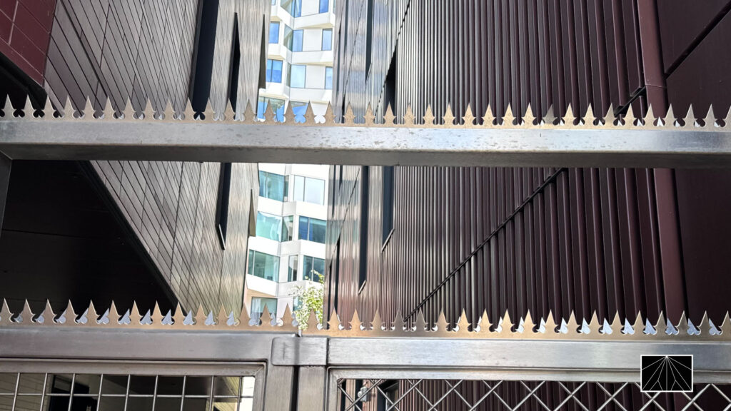 モダンな建築の間に設置されたステンレス製Ninja Deterrent™ハートデザインスパイク。都会的で洗練された防犯デザイン。