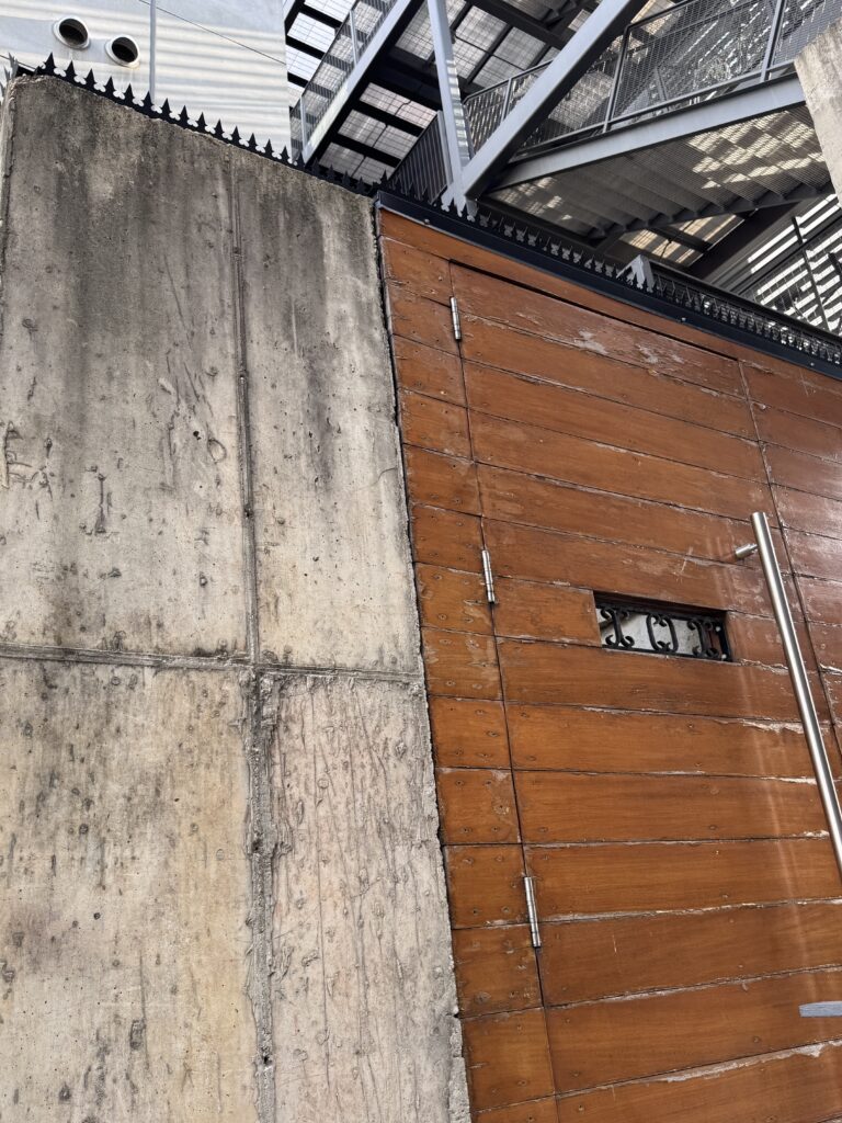 Full elevation of the wood gate with keypad, crowned by GIZAGIZA HEART across the entire span.