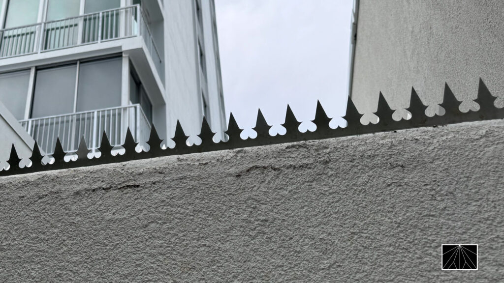 Ninja Deterrent™ Heart-design anti-climb spikes installed on a modern white concrete wall, combining minimal security and architectural aesthetics.