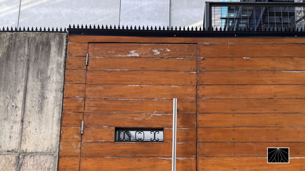 Ninja Deterrent™ Heart-design anti-climb spikes installed on a mixed wood and concrete wall, blending security with warm architectural texture.