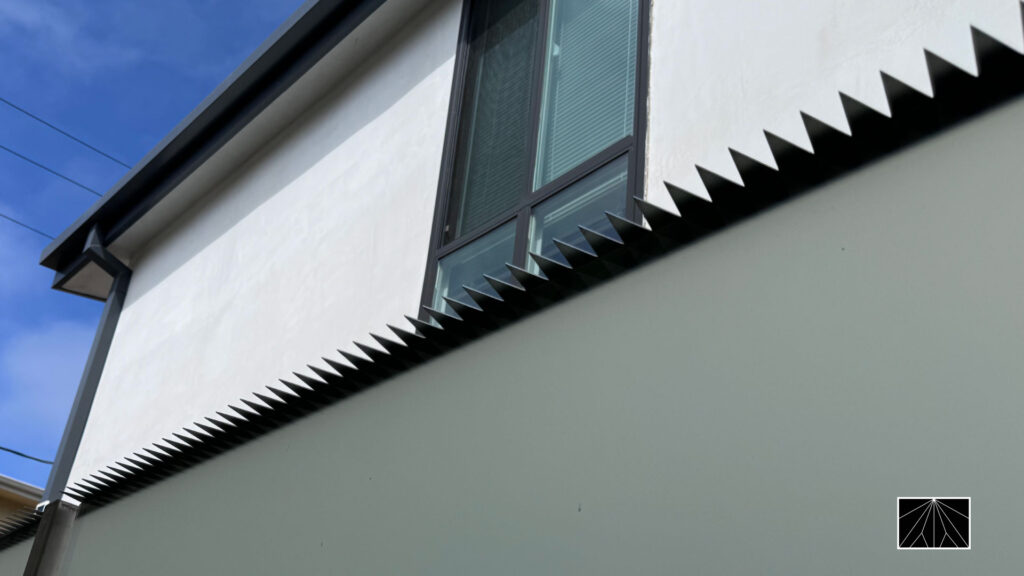 Anti-climb security spikes installed on a modern privacy wall outside a home in Santa Monica