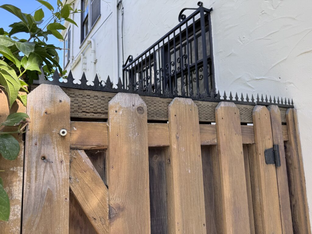 Close-up of the gate’s top edge showing anti-climb security spikes and hinge area.