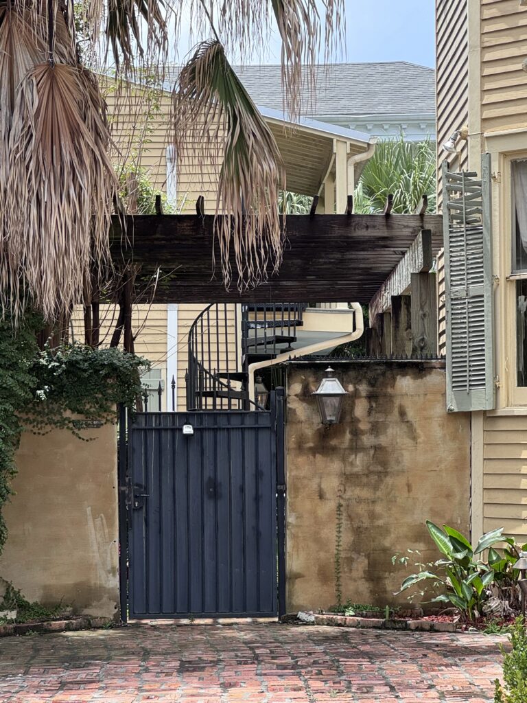 Púas de seguridad negras antiescalada montadas en el borde superior de una valla de madera negra cerca de una señal de «Prohibido escalar».