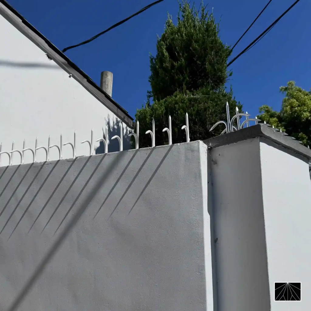Espigões de segurança Ninja Deterrent Classic brancos em parede branca, criando sombras que aumentam a dissuasão visual.