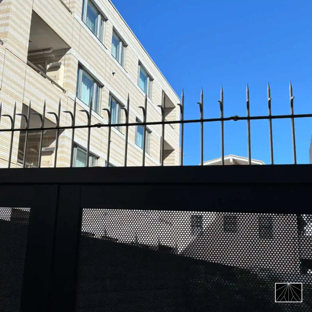 Espetos anti-escalada Ninja Deterrent em formato de lança, instalados em portão de condomínio urbano para segurança reforçada.