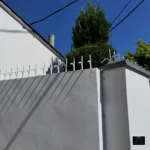 Weiße Ninja Deterrent Abwehrspitzen auf einer weißen Mauer mit markantem Schattenspiel zur optischen Abschreckung.