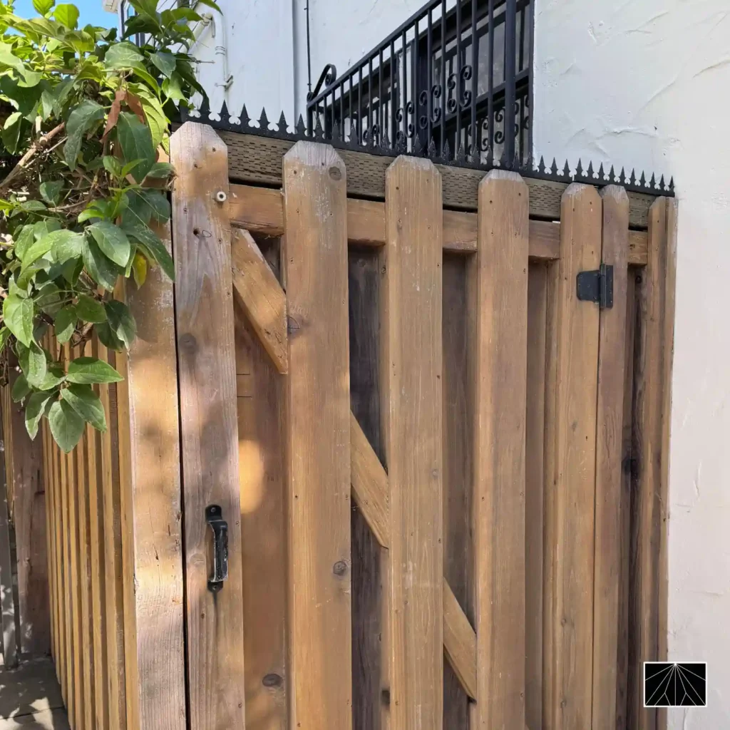 Détail des pointes de sécurité Ninja Deterrent Gothic en acier inoxydable noir sur un portail en bois robuste, alliant sécurité discrète et esthétique naturelle.