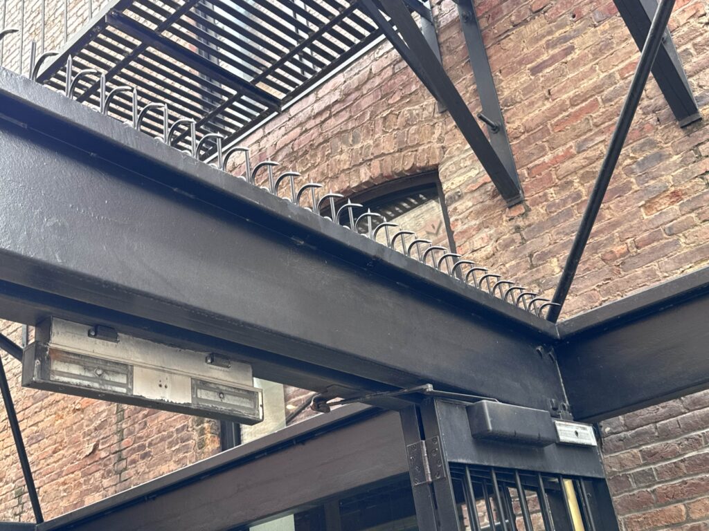 Entrée de café à San Francisco avec murs en briques, cadre de portail en acier noir et pointes Ninja Deterrent™.