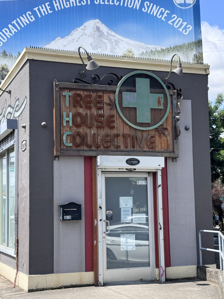 木製サインと緑の十字ロゴがある Tree House Collective の正面入口