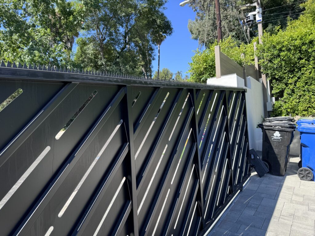 Schwarzes Schiebe-Einfahrtstor mit Anti-Climb-Spikes entlang der oberen Kante