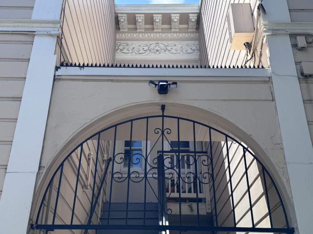 Ornamentierte obere Fassadenpartie über dem Bogen mit durchgehenden Anti-Kletter-Spikes und Zierprofilen.