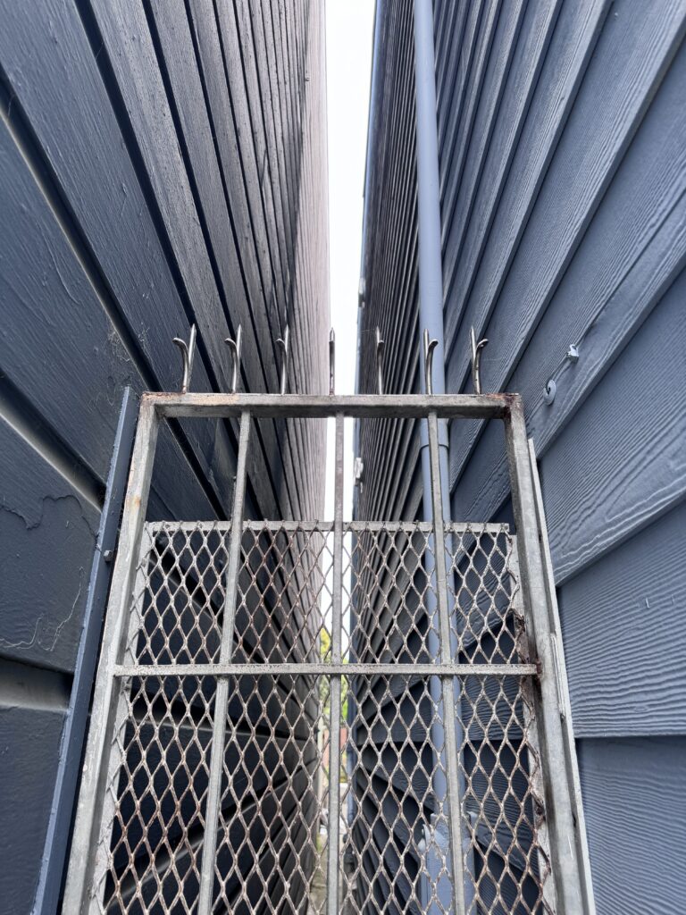 2棟の建物の間にある狭い路地に設置された、アンチクライムスパイク付き金属セキュリティゲート