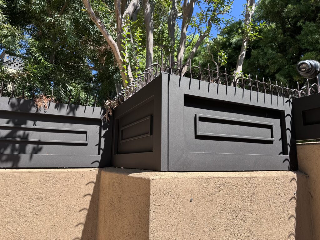 Wide corner view of the entry perimeter with continuous anti-climb spikes following the fence geometry
