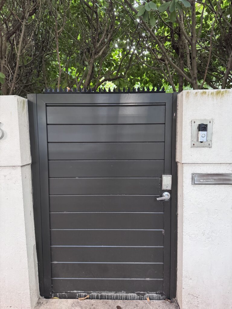 Front view of black wood condominium gate with continuous Gothic security spikes along the top edge