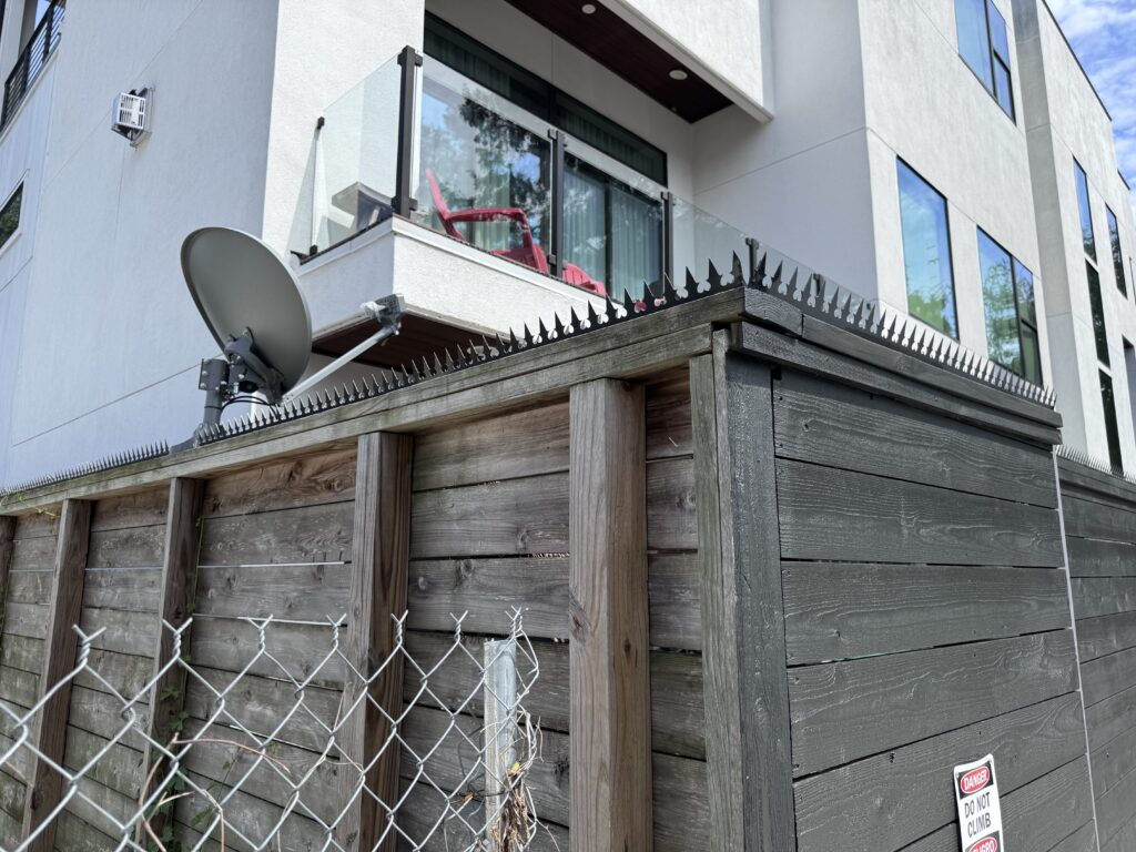 Longa cerca de privacidade preta com pontas anti-escalada em frente a uma casa moderna.