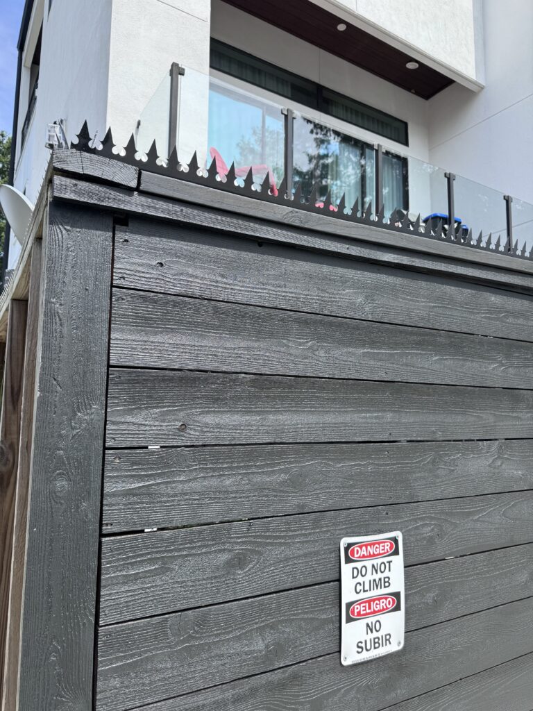 Esquina de la cerca con antena satelital y púas anti-escalada a lo largo del borde superior.