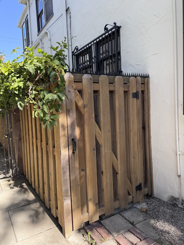 Primer plano del borde superior del portón mostrando las púas anti-escalada y la zona de bisagras.