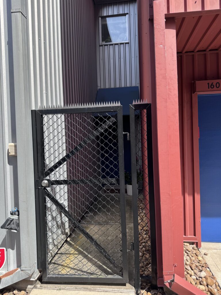 Beco residencial entre prédios modernos com garagens, céu limpo acima.