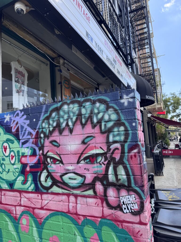 상점과 화재 대피계단 옆 벽화 벽 상단을 Gothic 블랙 스파이크가 크라운처럼 덮는 근접 뷰